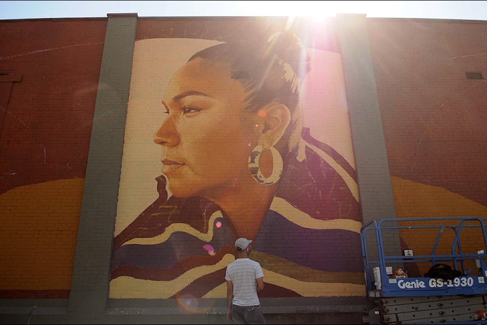 Artist Kevin Ledo steps back to look at his mural of Inez Louis while painting it on the back of a building on Victoria Avenue in downtown Chilliwack on Saturday, Aug. 15, 2020. (Jenna Hauck/ Chilliwack Progress)