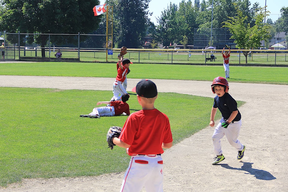 The Cloverdale Spurs Tadpole team (U8) field the ball in a game against the Ridge Meadows Royals June 27 at Cloverdale Ball Park. On this play, the Spurs’ second baseman (glove in the air) snags a pop fly as a Ridge Meadows baserunner darts back to first. (Photo: Malin Jordan)
