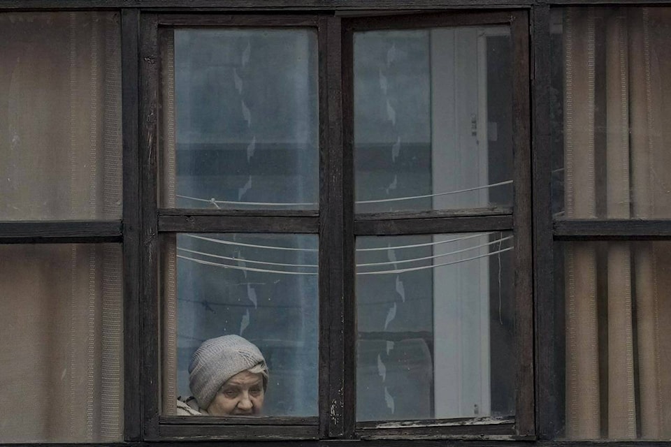 A woman looks out of the window of a balcony in Sievierodonetsk, in the Luhansk region, eastern Ukraine, Friday, Feb. 18, 2022. Spiking tensions in eastern Ukraine on Friday aggravated Western fears of a Russian invasion and a new war in Europe, with a humanitarian convoy hit by shelling and pro-Russian rebels evacuating civilians from the conflict zone. (AP Photo/Vadim Ghirda)