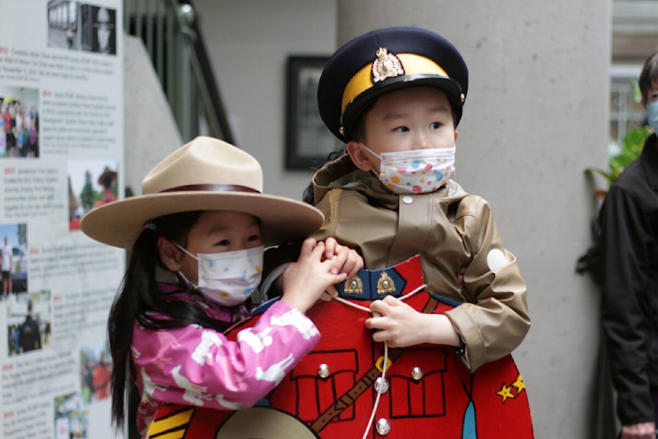 Shannon Sun, 5, and Jacob Lui, 4, pose with a cardboard cutout of the RCMP’s red serge during the Surrey RCMP Open House on Saturday (May 14, 2022). (Photo: Lauren Collins)
