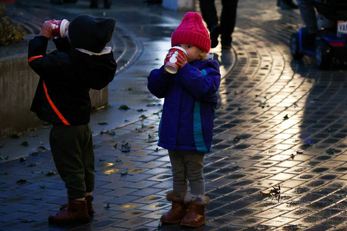 Two young children drink hot choclate at the Christmas on the Peninsula festival in Miramar Village Plaza in White Rock on Nov. 26. (Photo: Anna Burns)