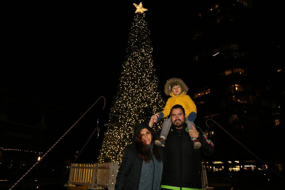 A man, woman and child pose for a photo in front of the christmas tree the Christmas on the Peninsula festival in Miramar Village Plaza in White Rock on Nov. 26. (Photo: Anna Burns)