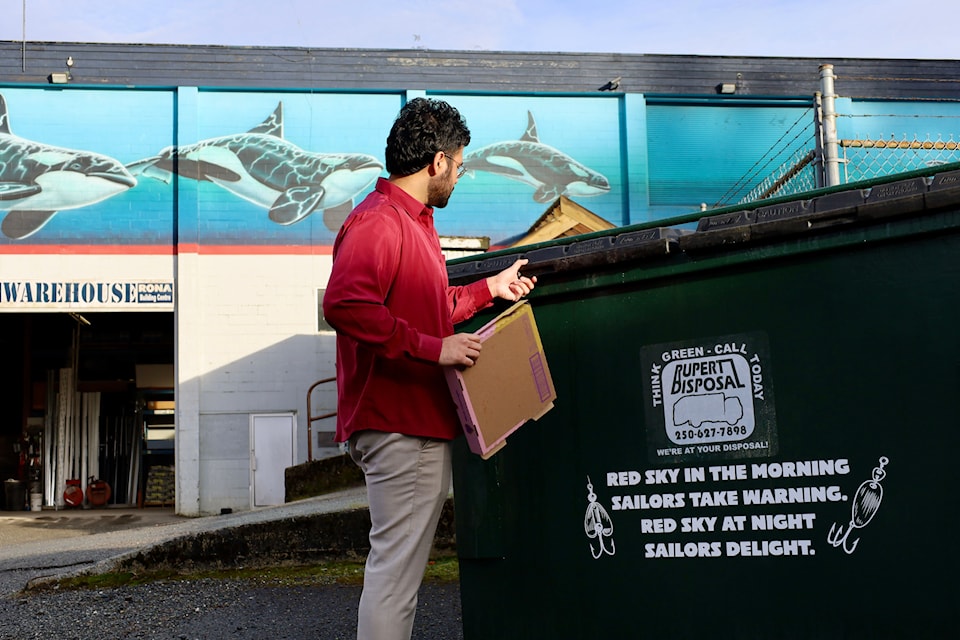 A resident of Prince Rupert recycles his cardboard in a Rupert Disposal bin. 
