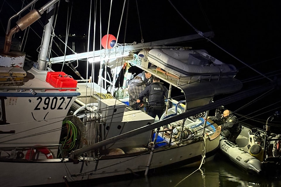 Police board a stolen fishing vessel after a suspect ran it aground near Prince Rupert on June 16.