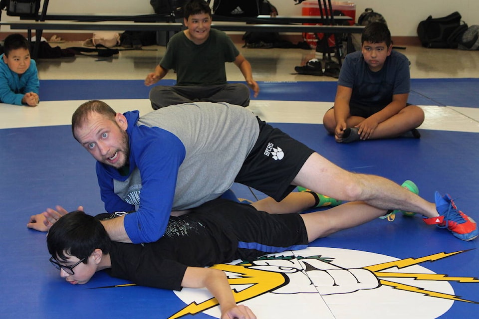 Charles Hays wrestling team head coach Dane Waldal demonstrates a take-down technique on the school’s new wrestling mats. (Alex Kurial / The Northern View)