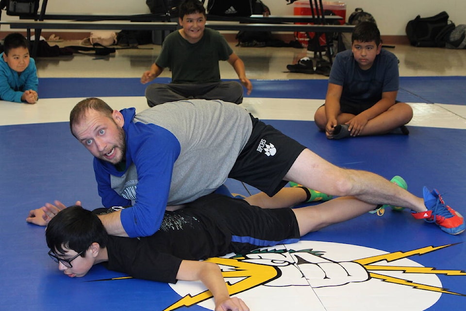 Charles Hays wrestling team head coach Dane Waldal demonstrates a take-down technique on the school’s new wrestling mats. (Alex Kurial / The Northern View)