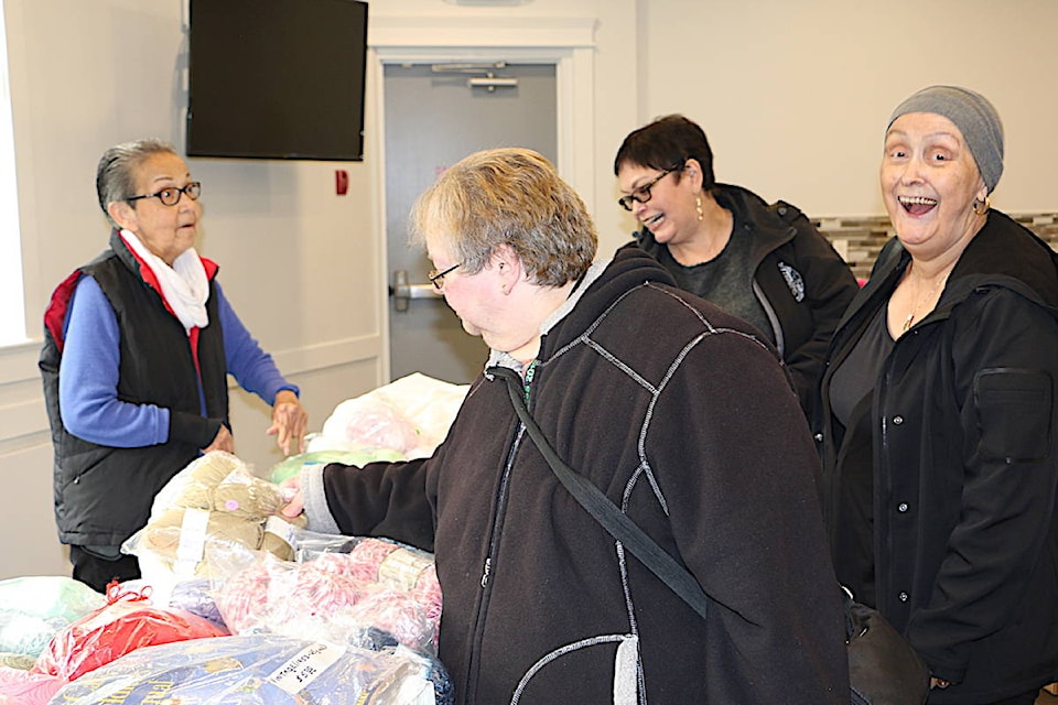 Eleanor Watts sells two handmaid eagle hats to Naomi White (second from right) who bought them as a gift for her twin granddaughters as Elaine Hughes (right) and Brenda Laidely (centre) look at her materials also on sale. (Jenna Cocullo / The Northern View)