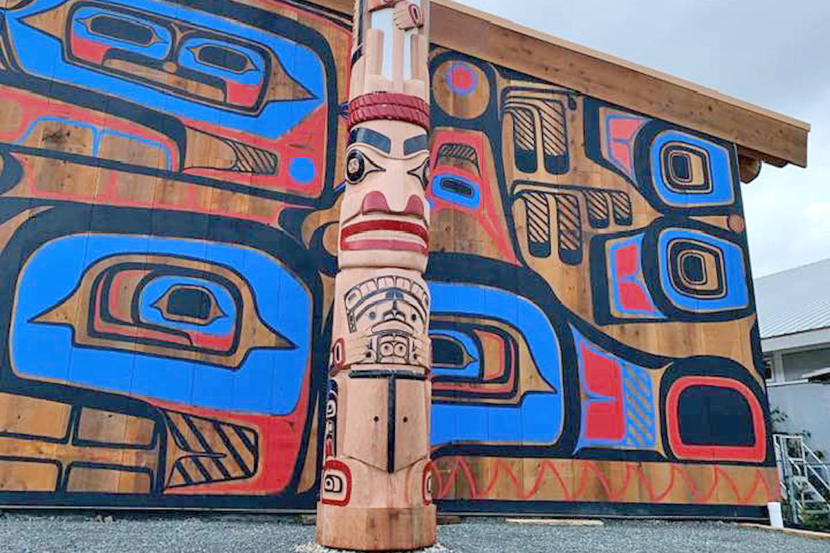 Haida totem pole in front of traditional Heiltsuk big house