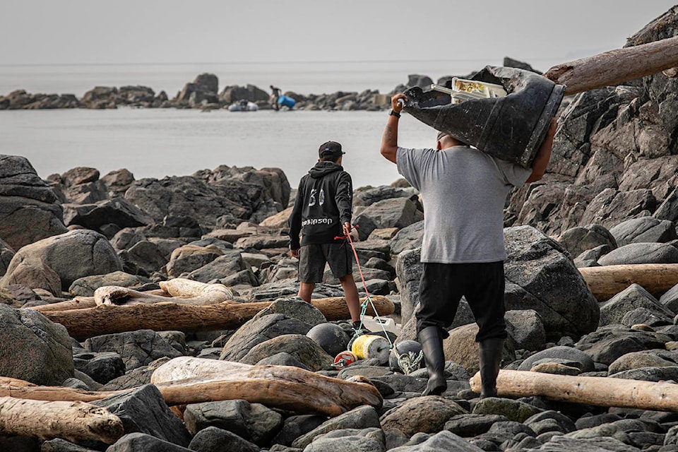 Dragging trash down the rocky beach. (Jack Plant photo)