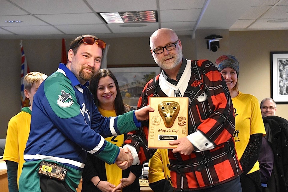Comox Mayor Russ Arnott (right) made good on his Mayor’s Cup wager at Monday’s Courtenay council meeting, presenting the “trophy” to Courtenay Mayor Bob Wells, while wearing a Don Cherry jersey, which Wells supplied. The fundraising hockey game, played Jan. 18, 2019, raised more than $16,000 for the Comox Valley branch of KidSport. Photo by Scott Stanfield