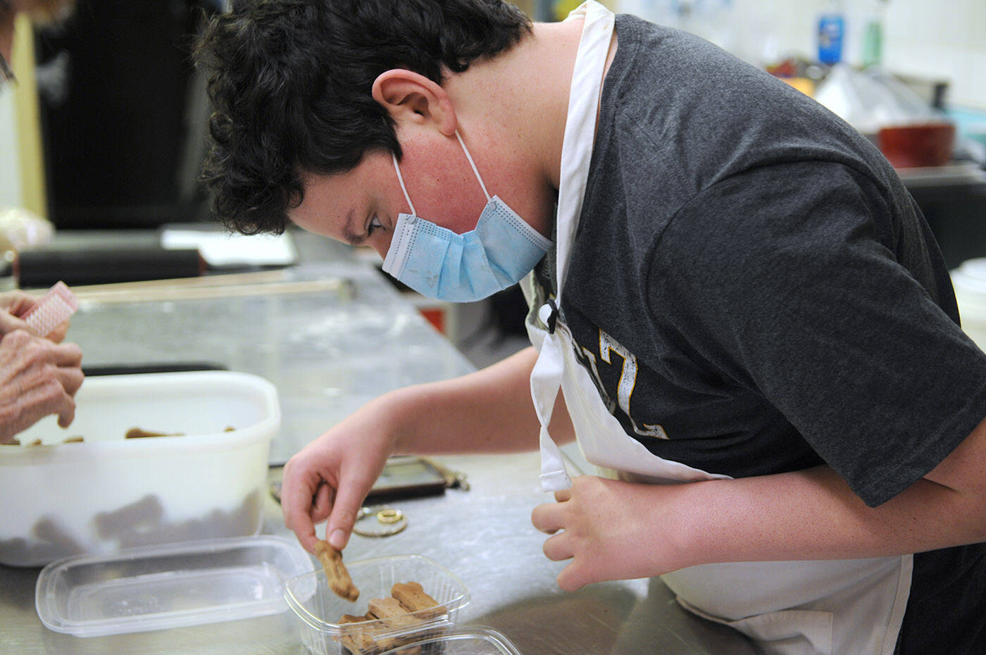 Ryder Newhouse, 14, packages up dog cookies at Fergies Doggie Delight Pet Bakery on Friday, Dec. 10, 2021. (Jenna Hauck/ Chilliwack Progress)