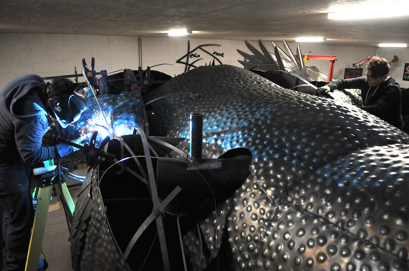 Brandon OShea (left) and Josh Guretzki work on the legs of Kevin Stones dragon on Dec. 1, 2022. (Jenna Hauck/ Chilliwack Progress)