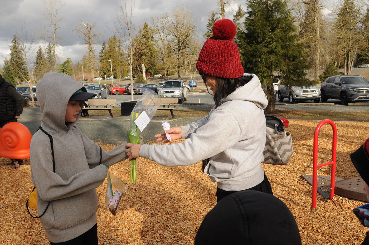 Rowan Sloan hands a woman a bunch of flowers at Vedder Park during Watson Elementarys Kindness Project on Wednesday, March 15, 2023. (Jenna Hauck/ Chilliwack Progress)