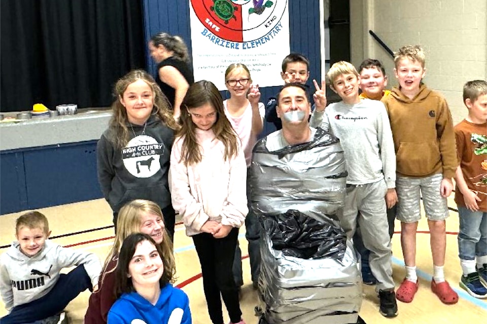 Barriere Elementary School students surround their duct-taped principal, Mikel Brogan who was in a 'sticky situation' on Oct. 7 as a reward for their efforts on Terry Fox Day. (Students from L - R): Nathan Banzaru, Emily Pidcock, Brinley Kuppers, Jessie Vansicle, Isabelle Young, Brielle Collins, Weston Salle, Max Hartfeld, Abraham Bourassa, and Logan Stewart.