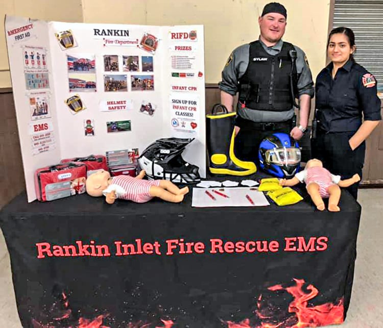 Bylaw officer and firefighter Capt. Kyle Lowe and medic Grachel D’Cuhna, right, represent the Rankin Inlet Fire Rescue EMS at the annual health fair at the community hall in Rankin on May 7, 2019. Photo courtesy Mark Wyatt.