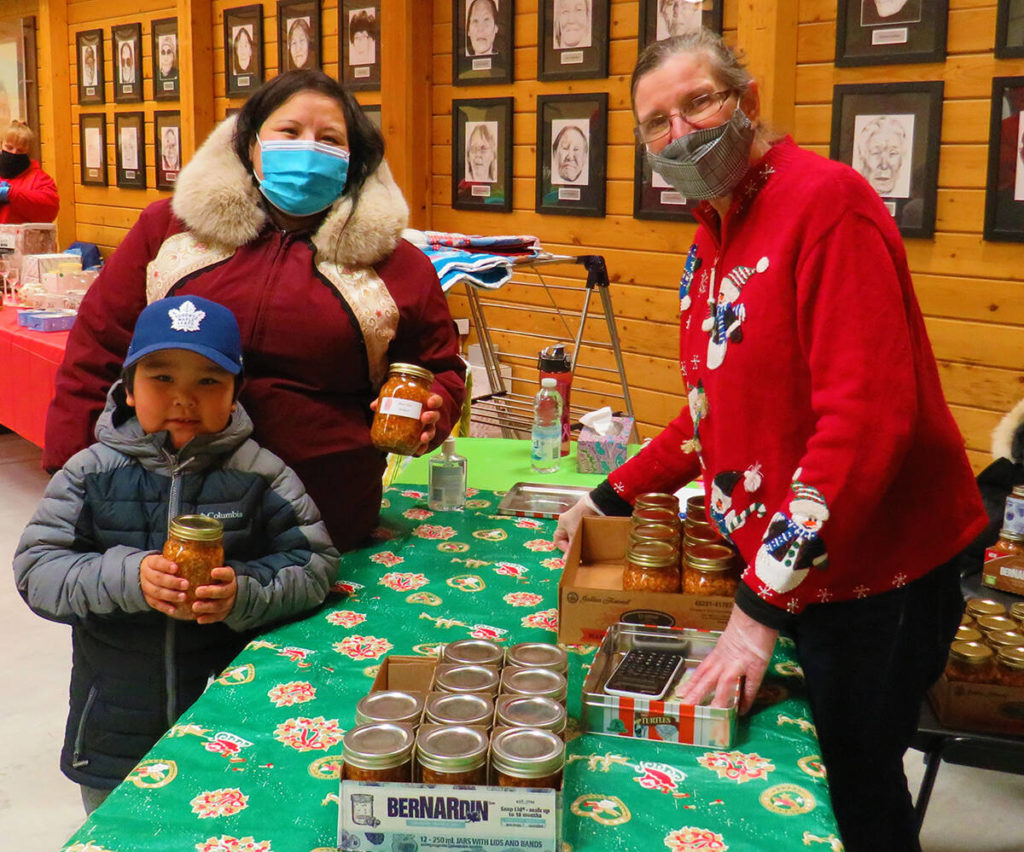 Yummy! Every year Roni Ohokannoak’s Arctic char antipasto is so popular at Cambridge Bay’s annual Christmas Bazaar. Here is Jenna Kamingoak and her 5-year-old nephew Darnell Kudlak Anablak getting some antipasto to enjoy over the holidays. Navalik Tologanak/NNSL photoᒪᒪᖅ ! ᐊᕐᕌᒍᑕᒫᑦ ᕌᓂ ᐅᕼᐅᑲᓐᓄᐊᑉ ᐃᖃᓗᖕᒥ ᓂᕿᓕᐊᖓ ᒪᒪᕆᔭᐅᓗᐊᒧᑦ ᐃᖃᓗᒃᑑᑦᑎᐊᕐᒥ ᐊᕐᕌᒍᑕᒫᒥ ᖁᕕᐊᓱᕖᖕᒥ ᓂᐅᕕᕋᕐᔪᐊᕐᓂᐅᔪᒥ. ᐅᓇ ᔨᐊᓇ ᑲᒥᙳᐊᖅ ᐊᒻᒪ ᑕᓪᓕᒪᓂᒃ−ᐅᑭᐅᓕᒃ ᐅᔪᕈᖓ ᑖᓂᐅᓪ ᑯᓪᓚᒃ ᐊᓇᑉᓚᒃ ᓂᕿᓕᐊᒥᒃ ᐱᔪᑦ ᒪᒪᑕᖕᓂᐊᖅᑕᒥᓂᑦ ᖁᕕᐊᓱᒡᕕᐅᑎᓪᓗᒍ .