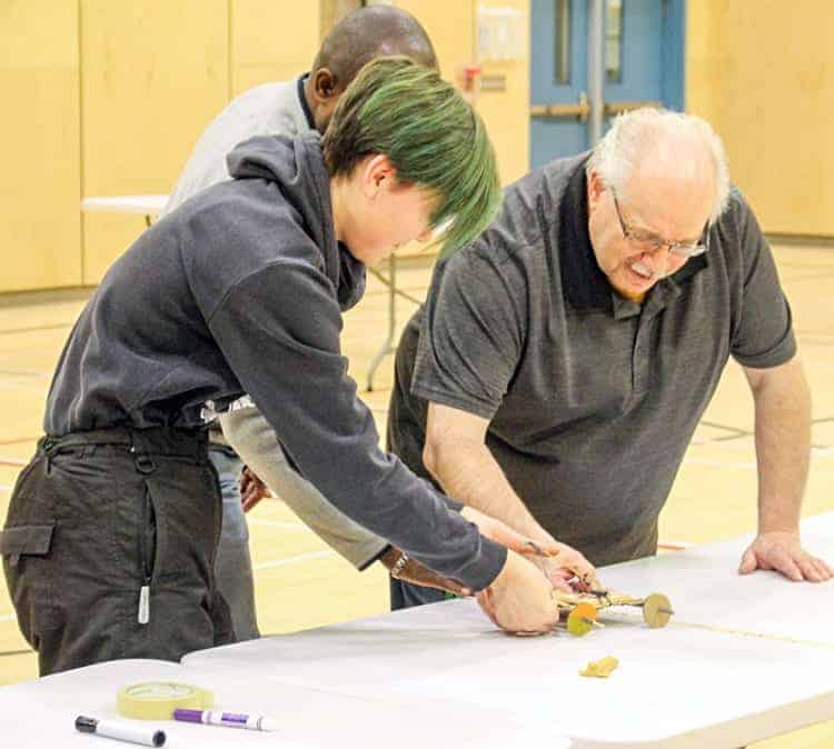 Student Kendra Kringayark tests out her project while teacher Gregg Durrant, back, and principal Aubrey Bolt measure the distance reached during the Acura STEM Challenge at Tuugaalik High School in Naujaat on Nov. 16, 2018. Photo courtesy Julia MacPherson