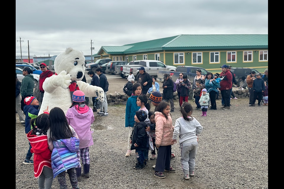 The polar bear mascot comes in for a bear hug with excited children in the barbecue line.