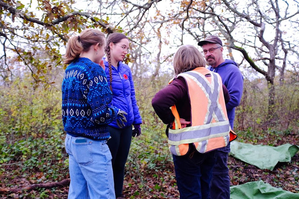 Margaret Lidkea, wearing an orange vest, discusses the game plan with volunteers for the remaining hour of a forest clean-up she organized as president of the Friends of Upland Park on Nov. 10, 2024.