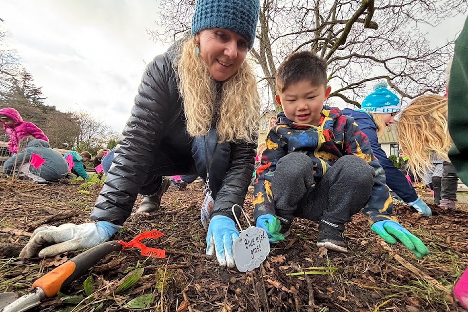 Kindergarten teacher Sally Hallam planting blue-eyed grass with one of her students.