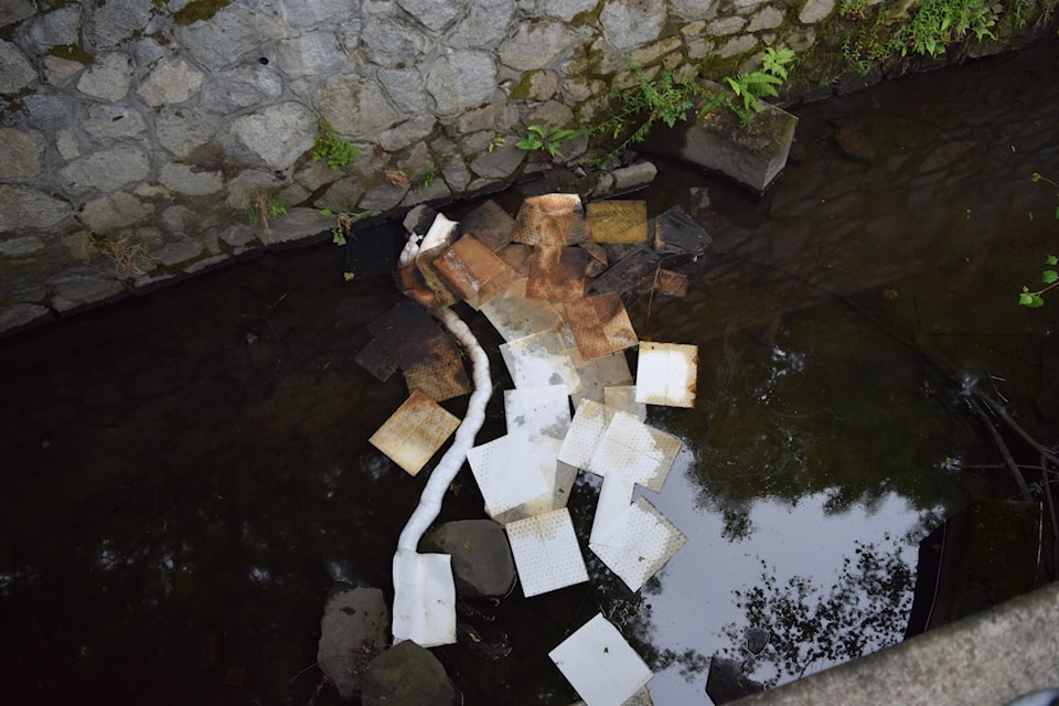 Floating barriers used to contain the pollutant, alongside absorbent pads, mark parts of the narrow waterway.