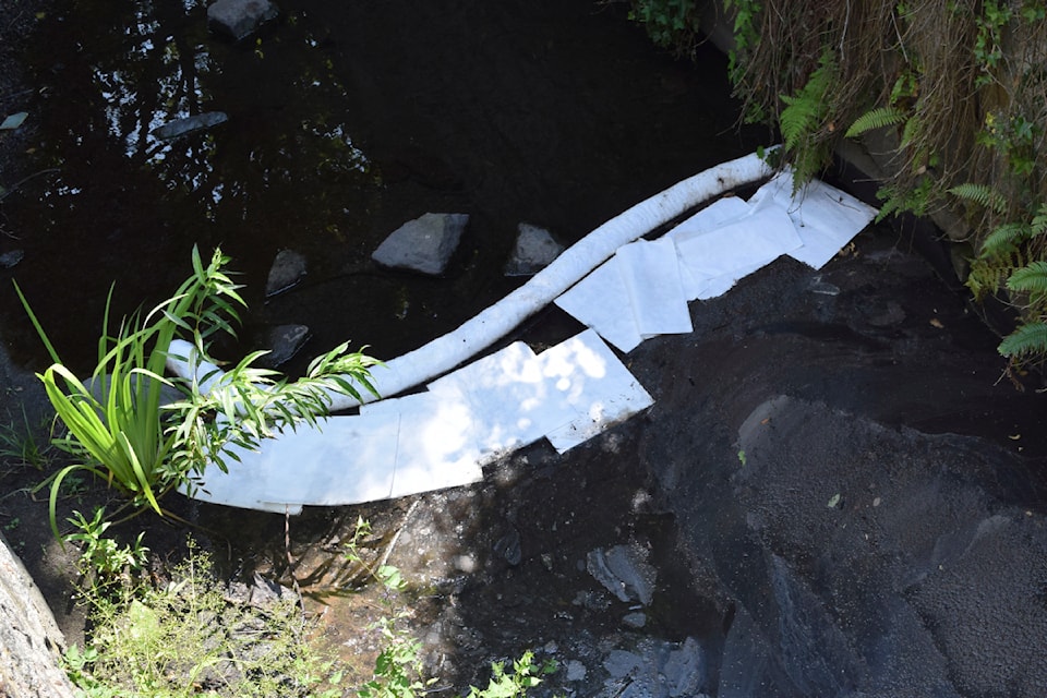 Booms and sorbent pads used to soak up contaminants mark Bowker Creek.