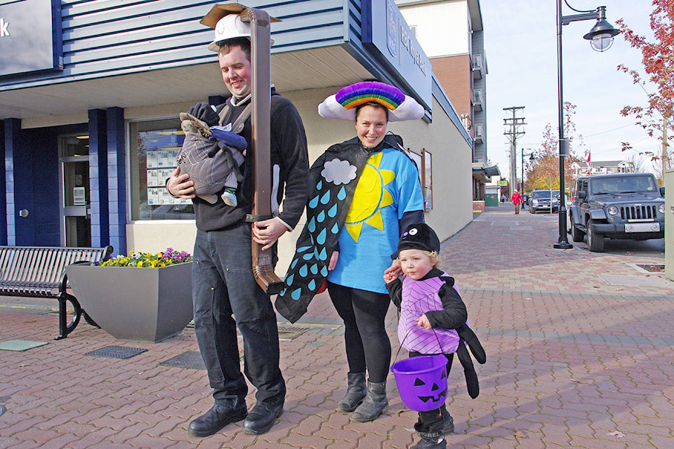 A pair of itsy bitsy spiders Magnolia, five weeks, and Hugh, 2, join dad (and waterspout) Josh Brand and mom Laura McOrmond (sun and the rain) on Sidney’s Treat Street Halloween afternoon. (Steven Heywood/News staff