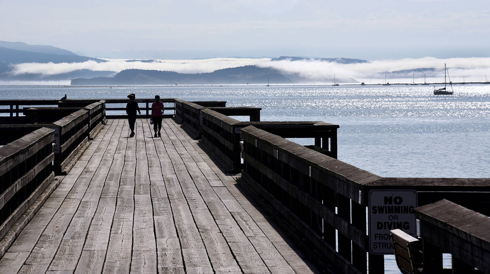 Pedestrians use the fishing pier along the Sidney waterfront. Don Denton photo