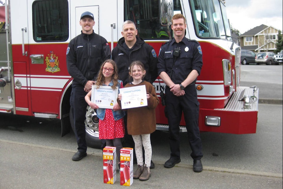 Langford firefighters stop by Happy Valley Elementary to surprise provincial contest winners Willa Roueche (left) and Tova Maguire. (Courtesy of Sooke School District)
