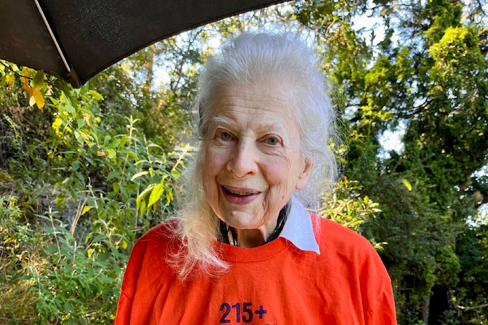 Marion Cumming shows off her Carey Newman-designed orange shirt under sunny skies in her Oak Bay garden on July 29. (Photo by Arifin Graham)
