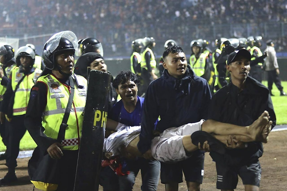 Soccer fans carry an injured man following clashes during a soccer match at Kanjuruhan Stadium in Malang, East Java, Indonesia, Saturday, Oct. 1, 2022. Clashes between supporters of two Indonesian soccer teams in East Java province killed over 100 fans and a number of police officers, mostly trampled to death, police said Sunday. (AP Photo/Yudha Prabowo)