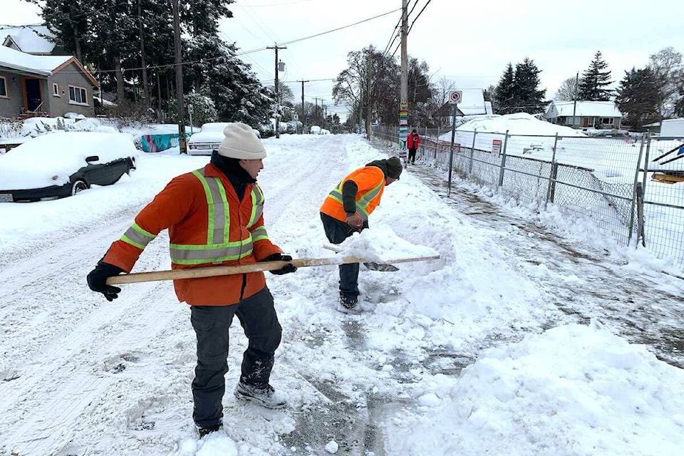 A worker gets creative amid Victoria’s snowstorm on Dec. 20 and uses a wooden sign to clear a path. (Jake Romphf/News Staff)