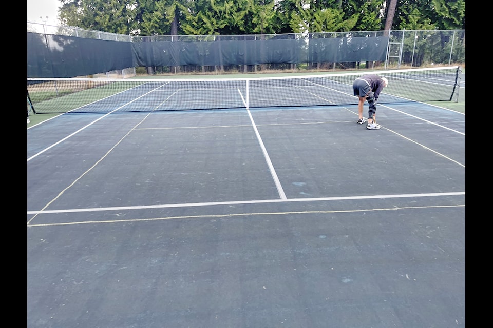 A member of the Arrowsmith Tennis Club scrubs pickleball lines drawn on the tennis court at Qualicum Beach. (Contributed photo)