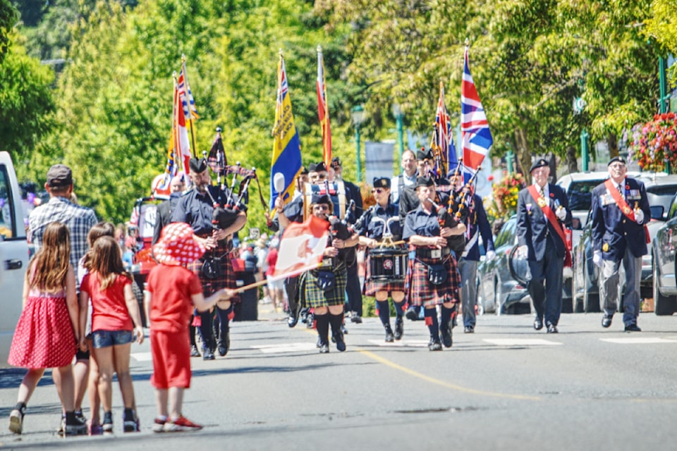 A youngster waves his flag in excitement as the Mount Arrowsmith Pipe Band leads the Qualicum Beach Canada Day Parade. (Michael Briones photo)