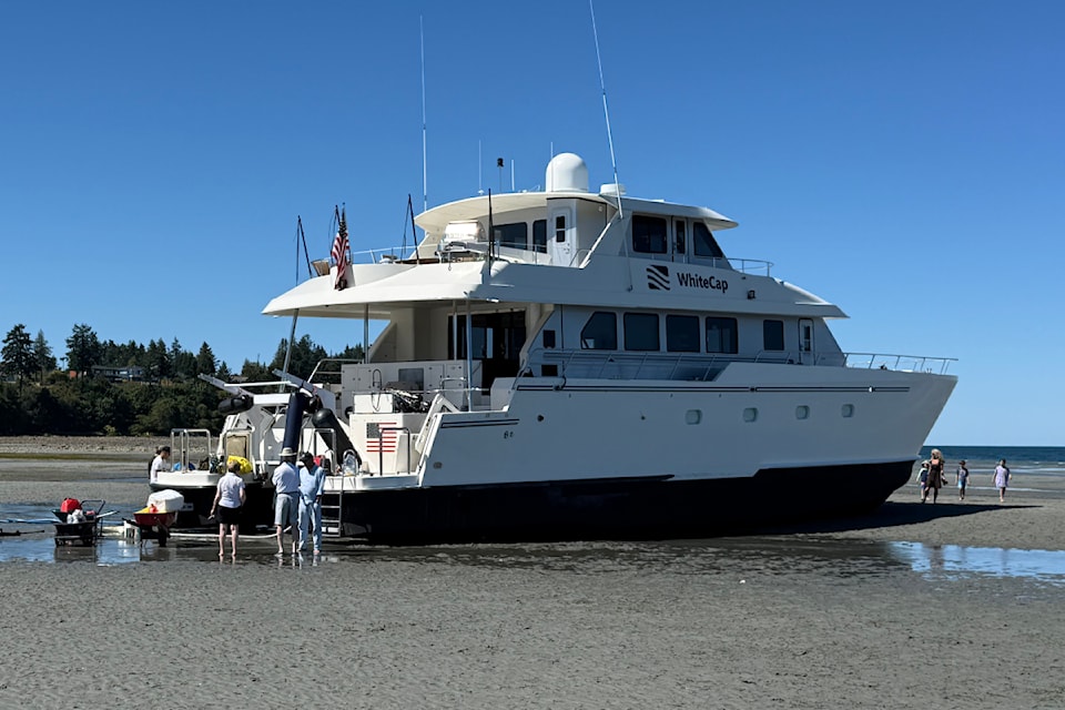 Curious onlookers gathered around a pleasure-craft which found itself stranded on Parksville Bay Beach on Aug. 11 before it was towed away by the Canadian  Coast Guard.