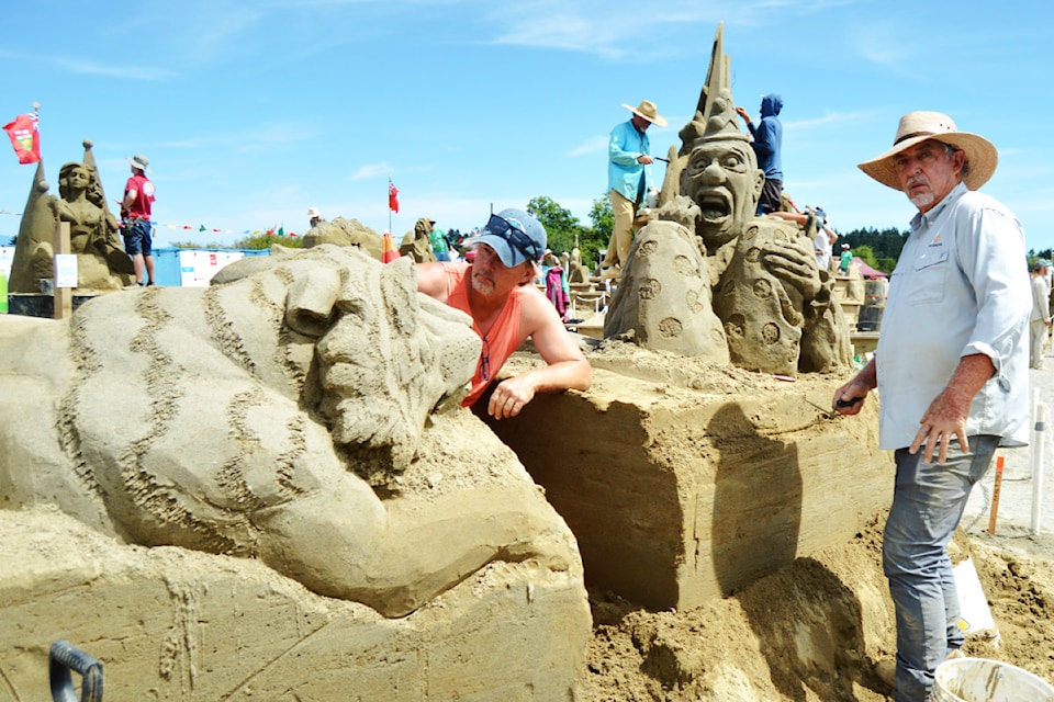 Sand sculptors work on finishing their art work at the 2025 Quality Foods Sand Sculpting Competition. 