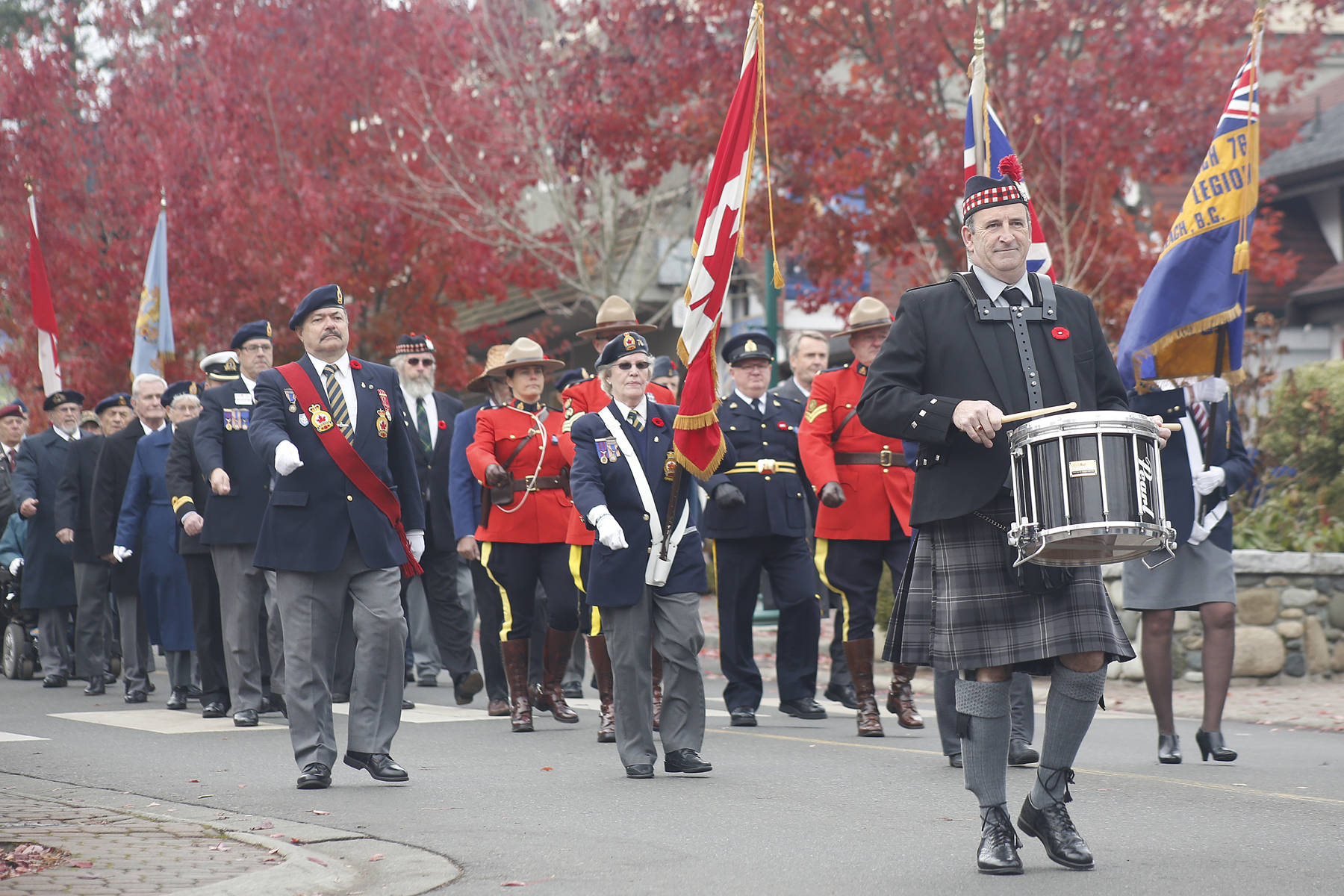 Cliff Reynolds, right, drums with the Qualicum Beach Pipe Band during the parade down to the Qualicum Beach legion after the ceremony. — Adam Kveton Photo