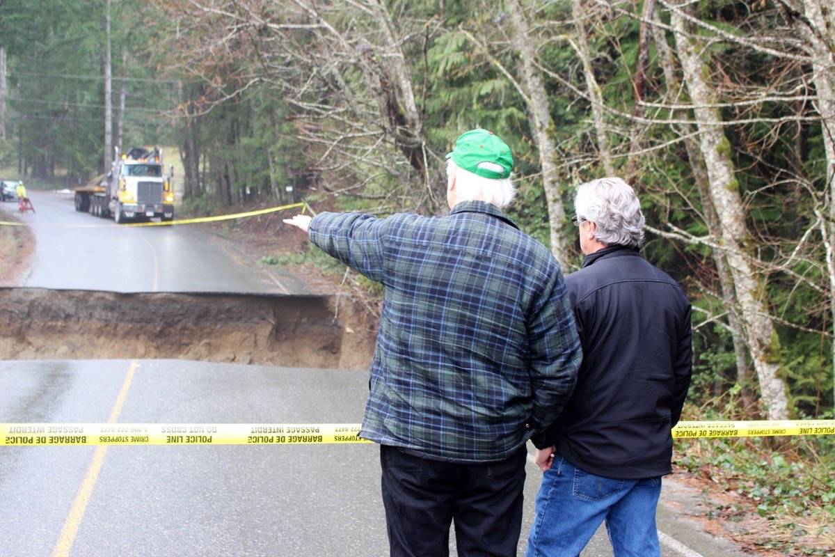 Regional District of Nanaimo Director Julian Fell, left, and board chair Bill Veenhof examine a seven-metre chunk of Melrose Road in Whiskey Creek was washed away when floodwaters overwhelmed a culvert overnight Sunday, Jan. 28, 2018. Crews were setting up barricades late Monday morning. — Lauren Collins photo