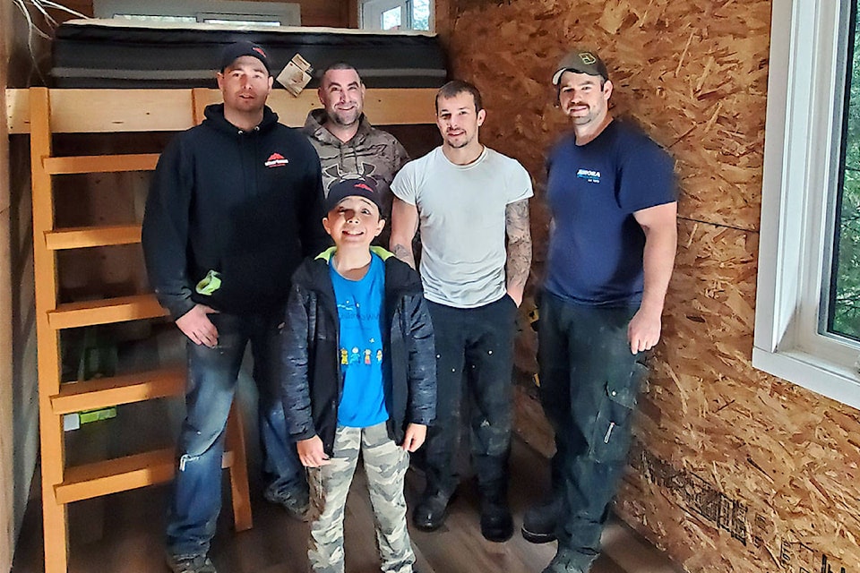 Brandon Ford, Ryan Smythe, Ritchie Rae and Kyle Meston stand behind Kai in his newly-built treehouse on Mayne Island. (Courtesy of Kevin Hennessey)