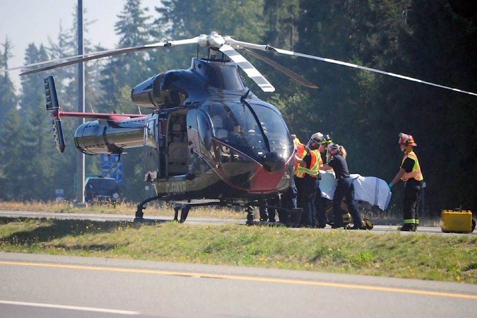 A person involved in an incident that resulted in a vehicle crashing into a ditch on the Island Highway near the Qualicum Beach offramp on Friday, Sept. 11 is taken to a waiting helicopter. (Michael Briones photo)