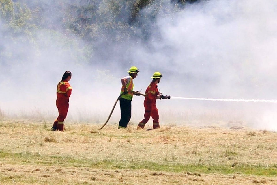 Coombs-Hilliers Fire Department crews work their way through the smoke as they try to contain a brushfire on a field at a property on Grafton Avenue on June 23. (Michael Briones photo)