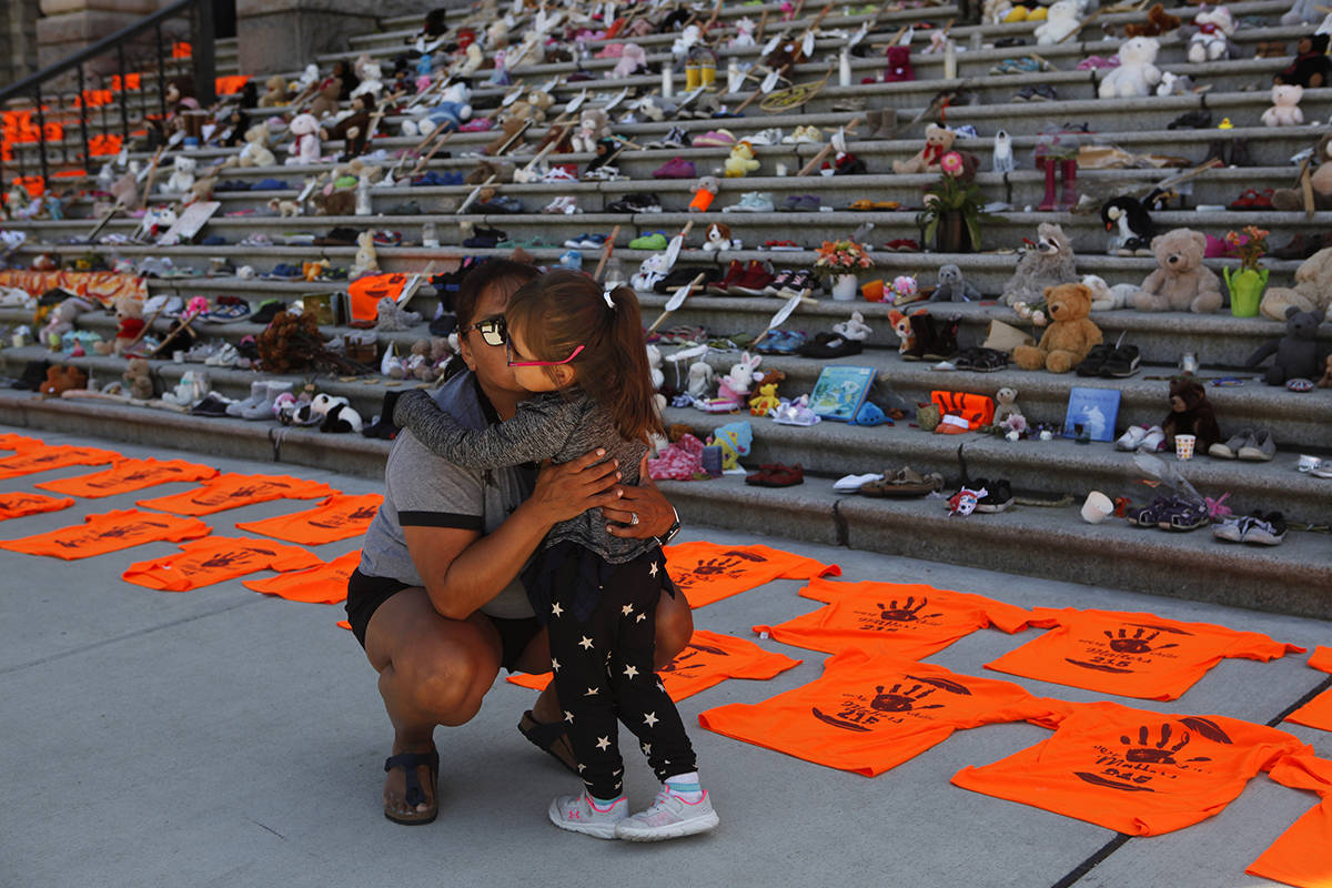 Emmy Morris who attended Indian day school and her mother who went to a residential school hugs her daughter Sharon Morris-Jones, 4, from the Tsartlip First Nation outside the legislature in Victoria, B.C., on Tuesday, June 8, 2021. THE CANADIAN PRESS/Chad Hipolito