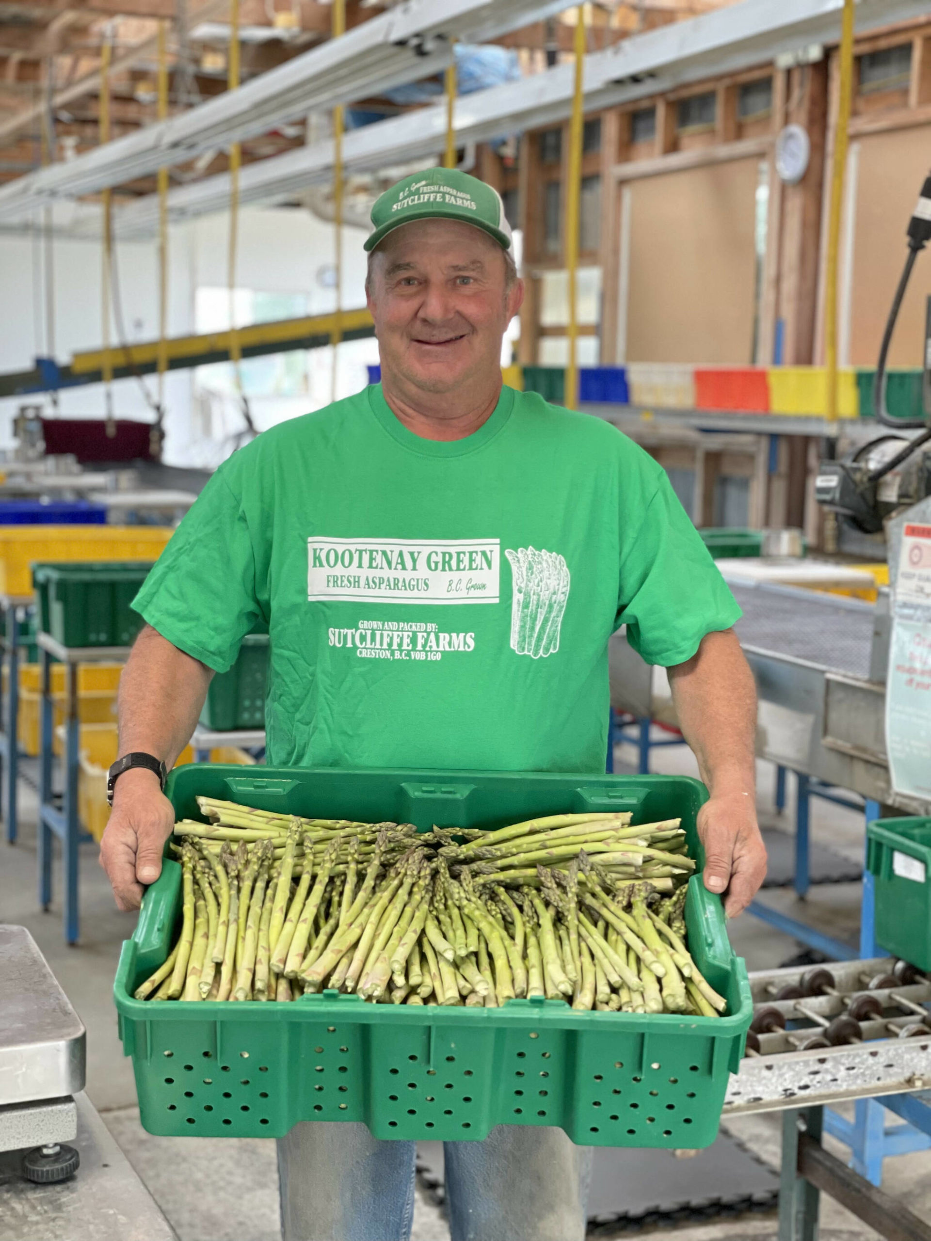 Doug Sutcliffe poses with a bin of freshly picked asparagus. (Photo by Kelsey Yates)