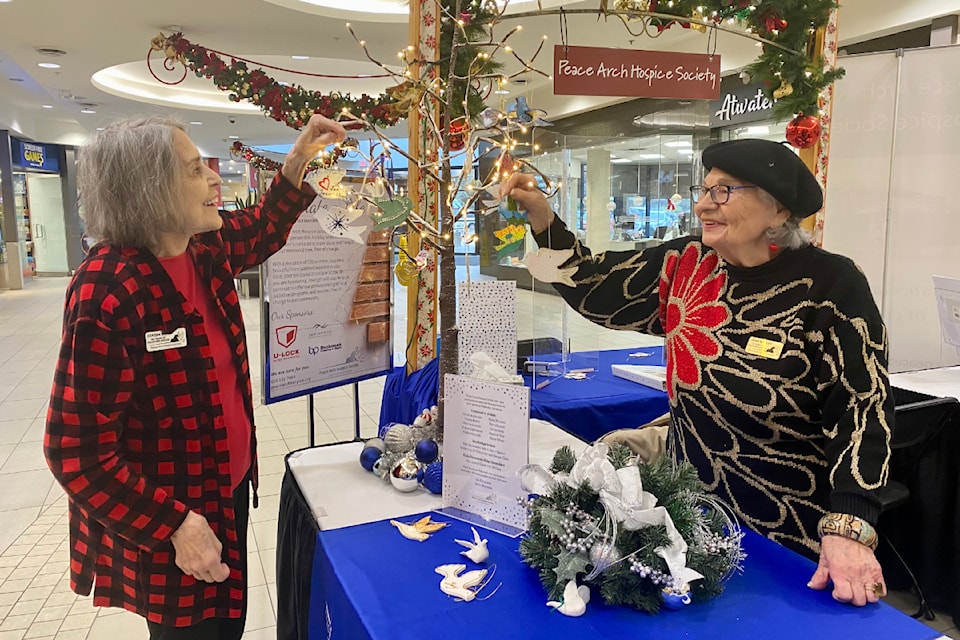 Longtime hospice volunteers Doreen Bruce and Jean Walker, on the first shift of the 2023 Celebrate a Life event, hang hand-painted wooden and clay doves.