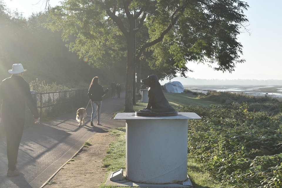  Linda and her canine companion Eloise walk past a dog sculpture on the White Rock promenade Thursday (Aug. 29) shortly after 7 a.m. A trial period of allowing dogs on the waterfront from 5:30 to 9 a.m. extends through September.