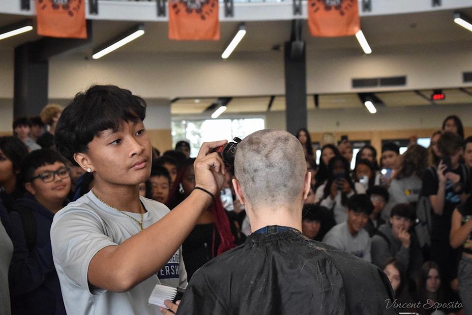 Grandview Heights Grade 11 student Christian Echon shaves staff member Karen Brett's head.