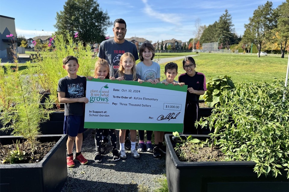 Students and Katzie teacher Zubin Haveliwalla stand with a cheque for their school garden.