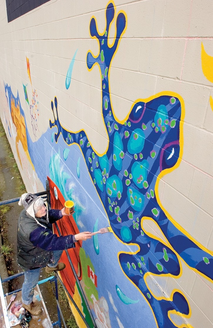 Elizabeth Hollick is painting a mural on the studio wall of Blue Frog Studio.