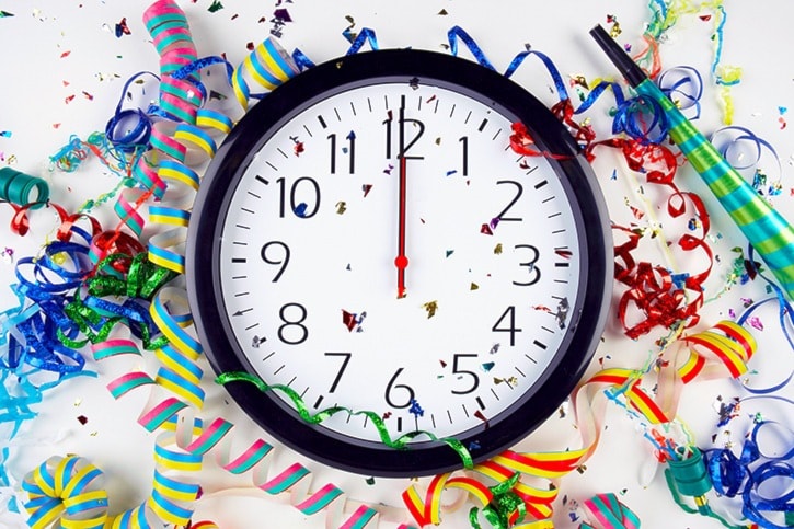 Clock showing midnight surrounded by confetti and ribbons