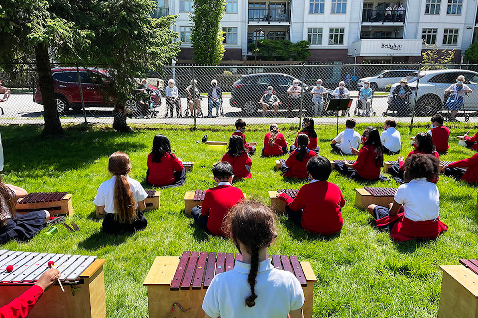 Students from Cloverdale Catholic School sit on school grounds while they play music for residents of Bethshan Gardens. So far students from every grade have played for the seniors in a series of music performances. (Photo submitted: Clive Heah)
